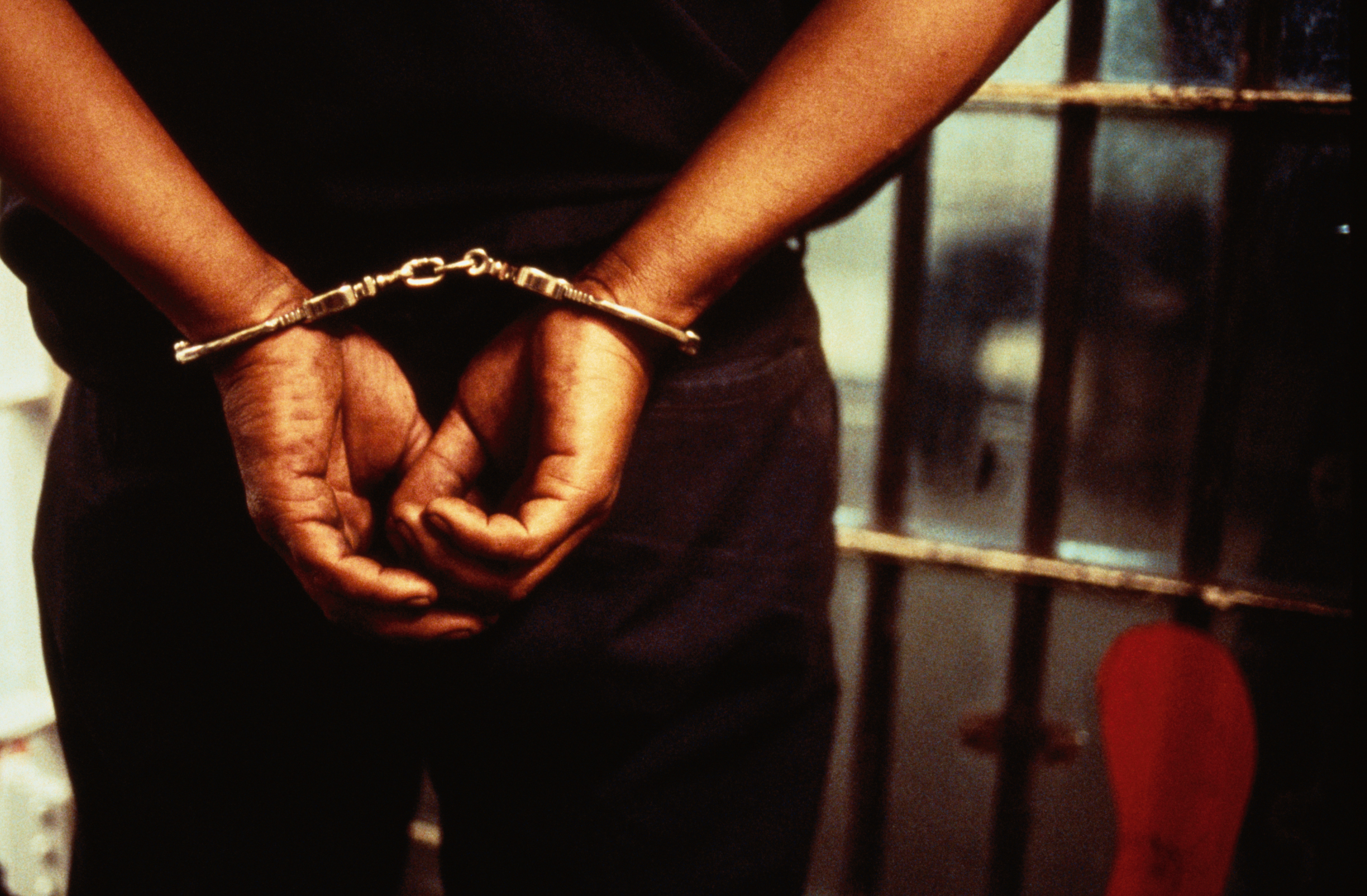 A teen in jail with his hands handcuffed behind his back