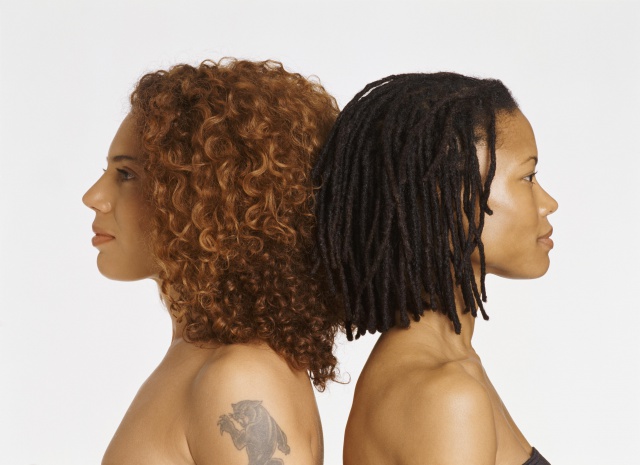 Studio Portrait of Two Young Women Back to Back, One With a Tattoo