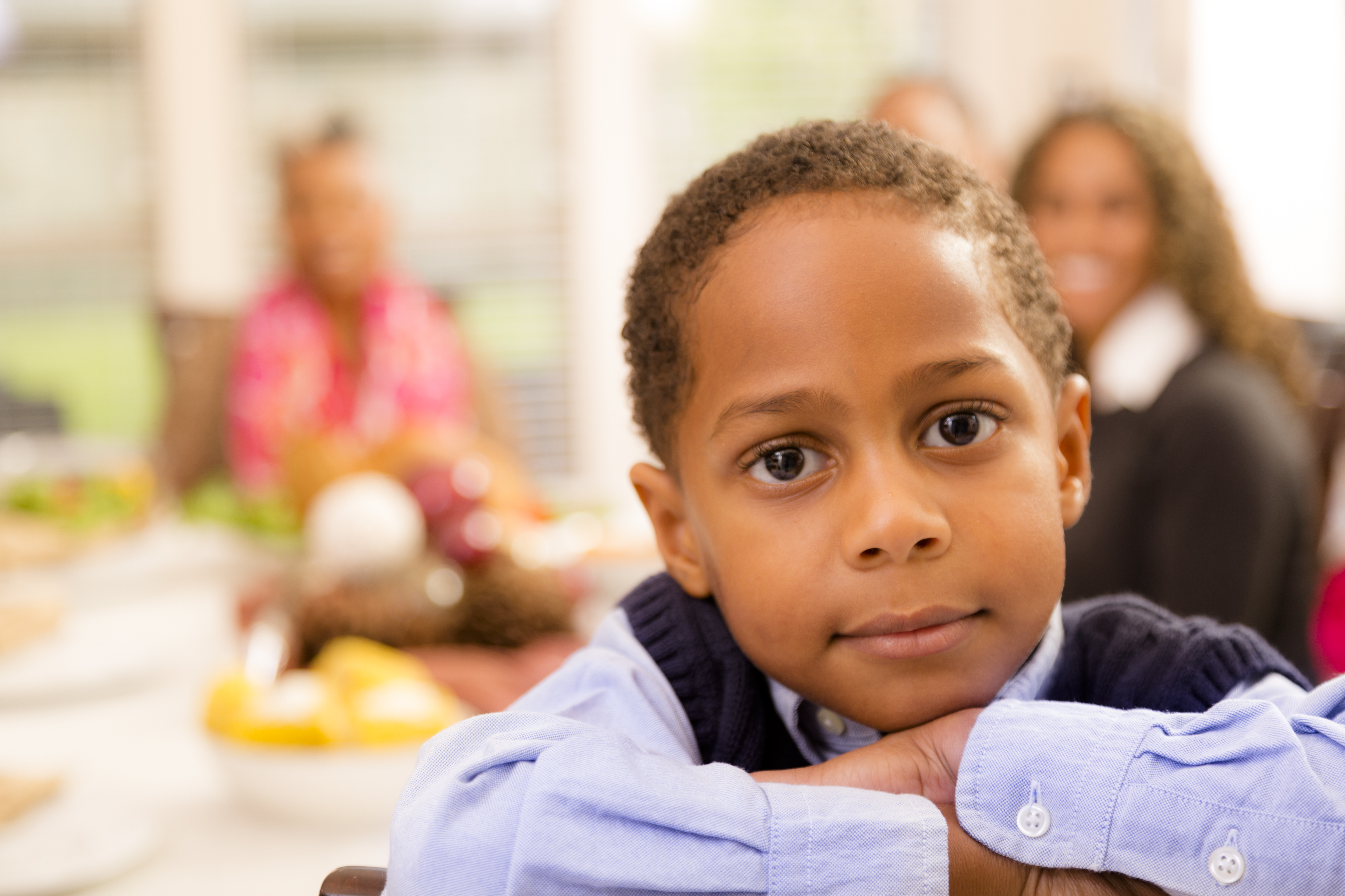 Family gathers for dinner at grandma's house. Little boy posing.