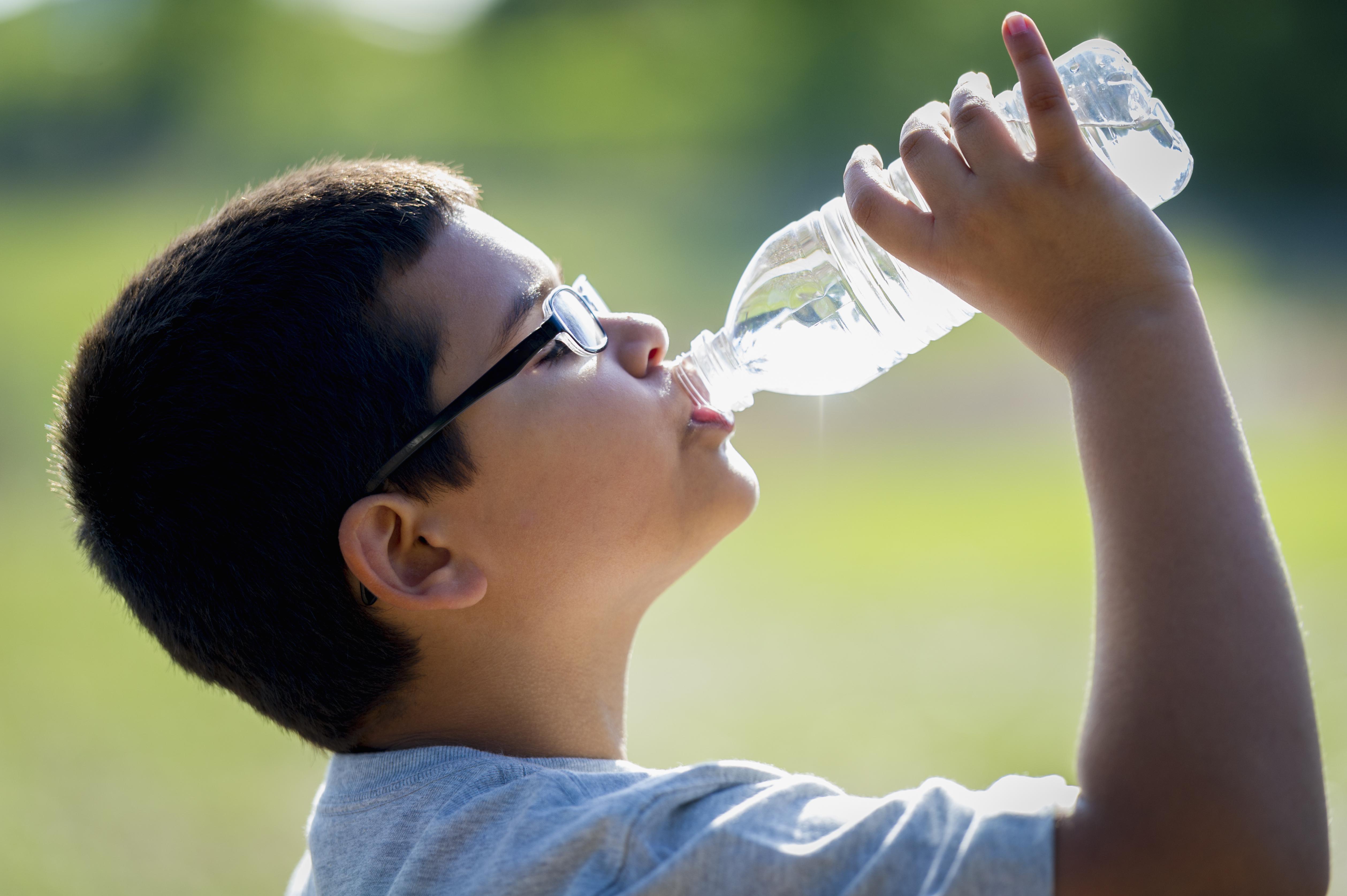Nine year old boy drinking water from a bottle