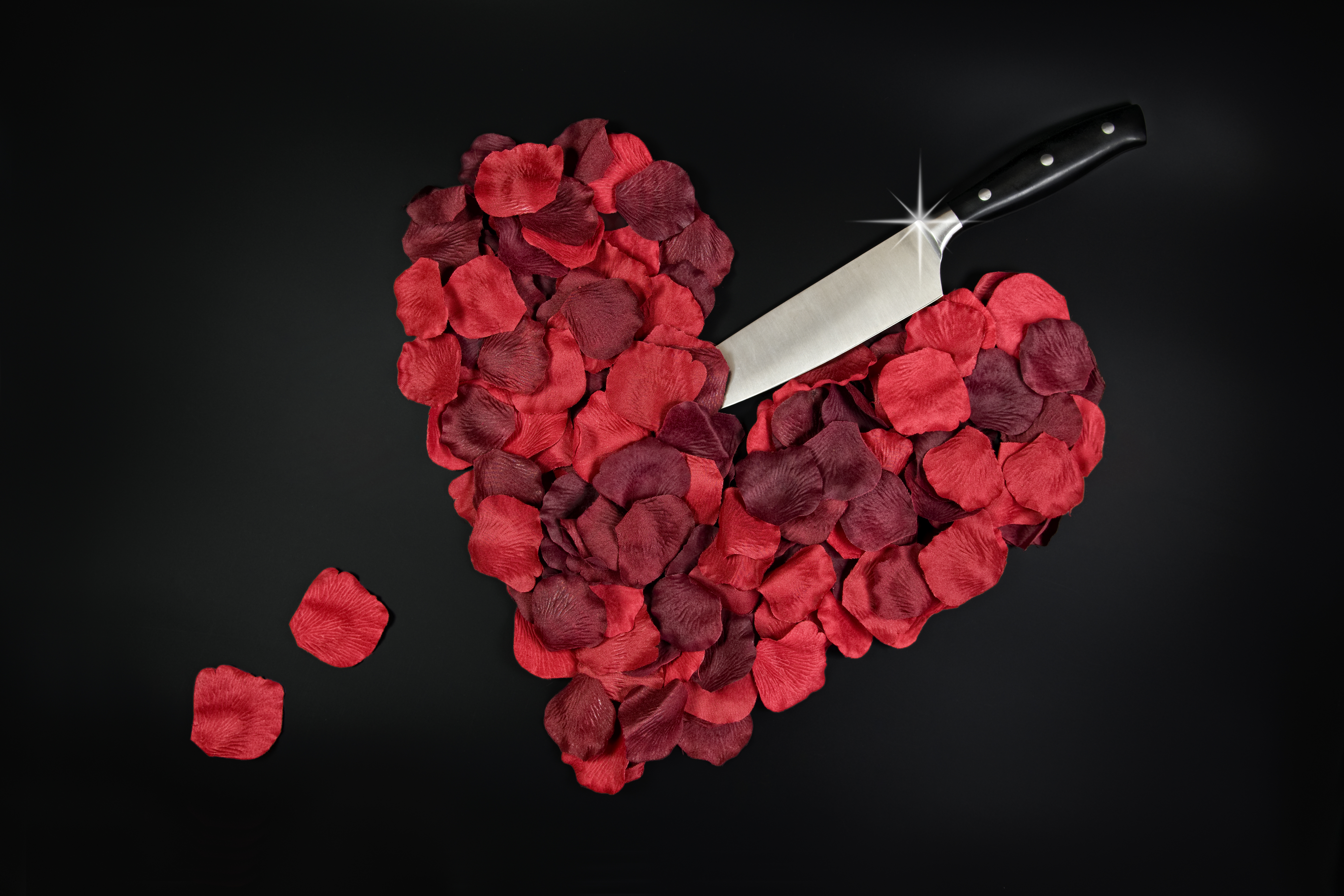 Red rose petals in heart shape with large knife