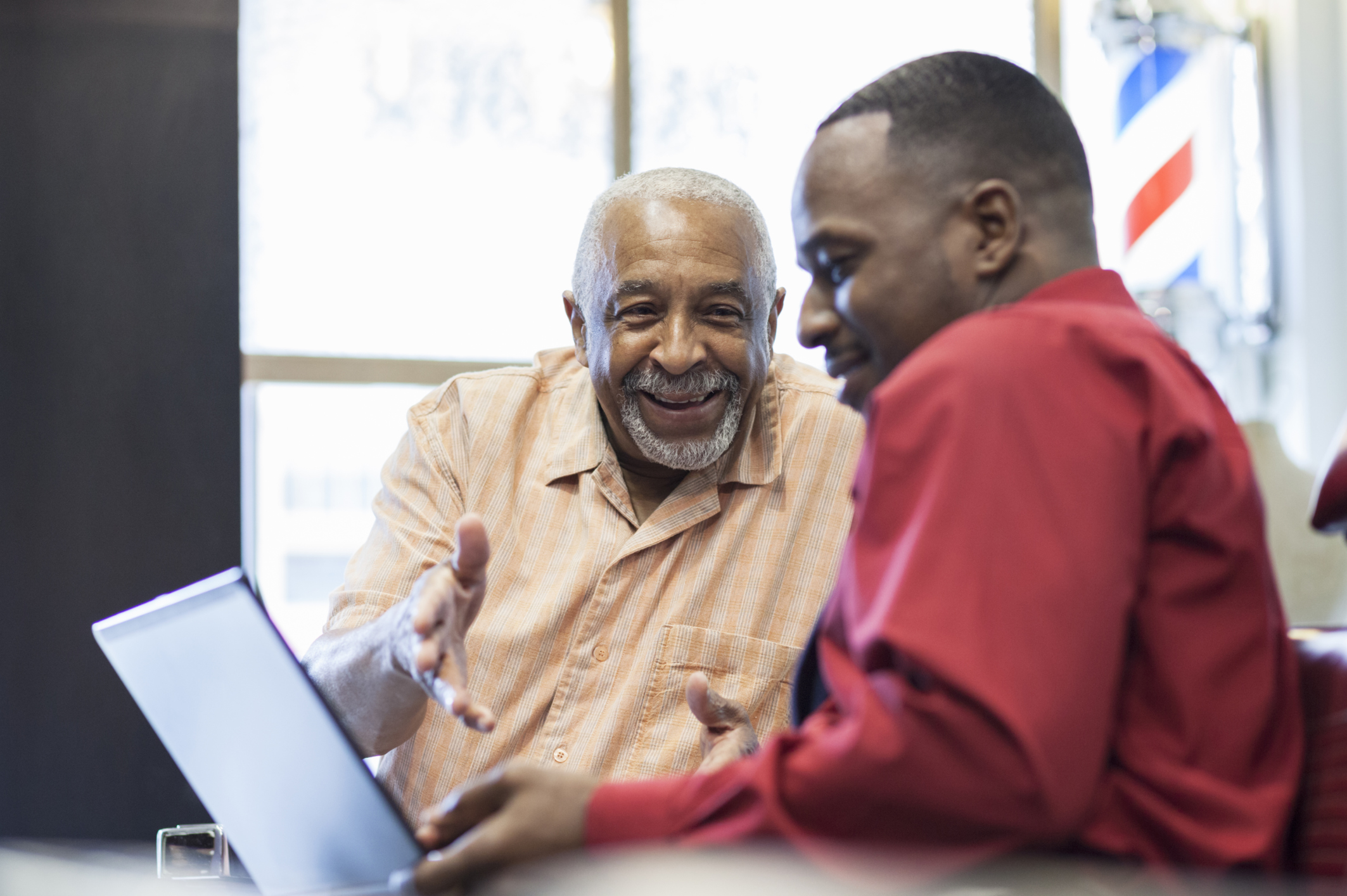 Black businessmen using laptop in retro barbershop
