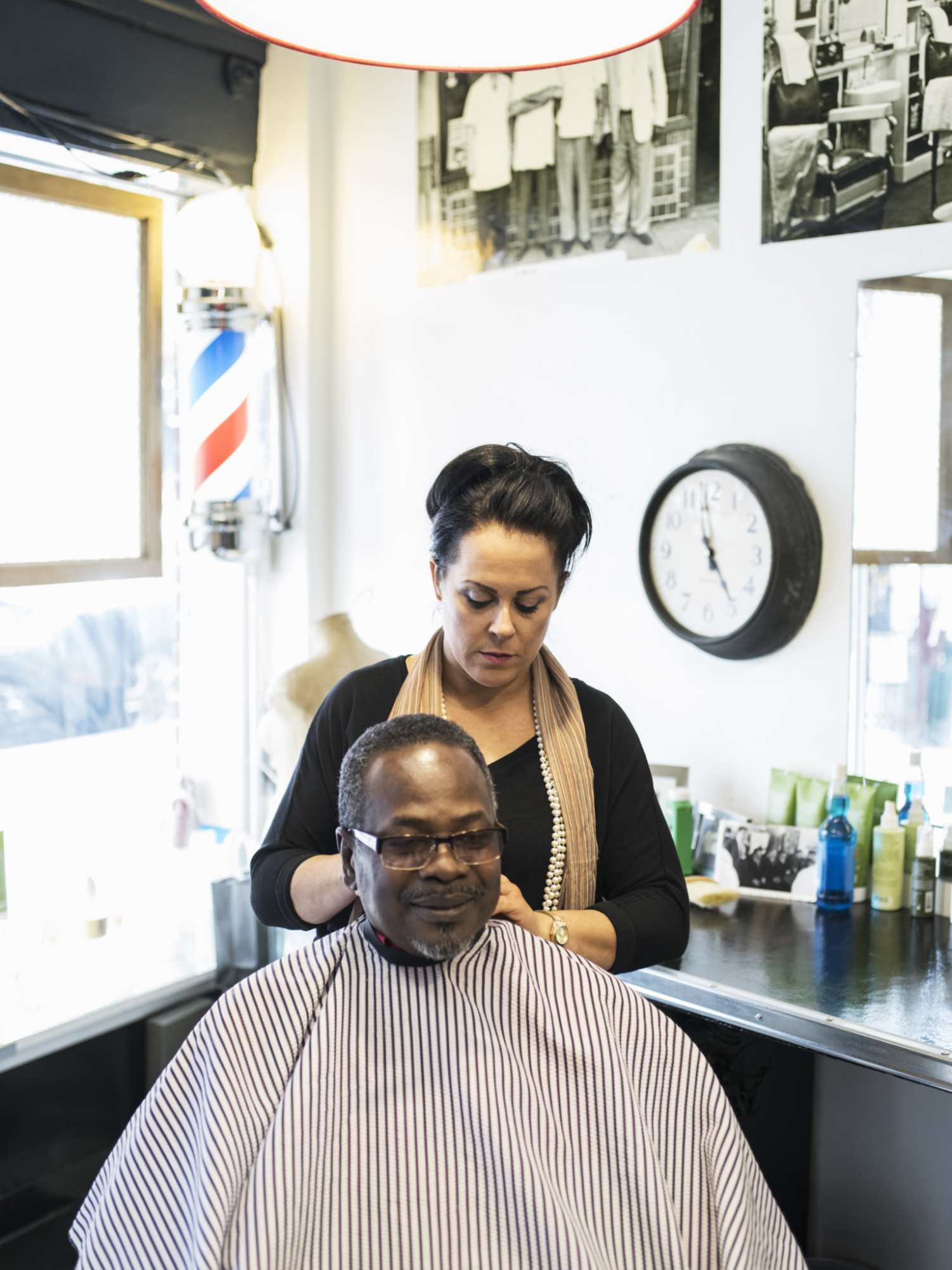 Hairdresser clipping hair of man in retro barbershop