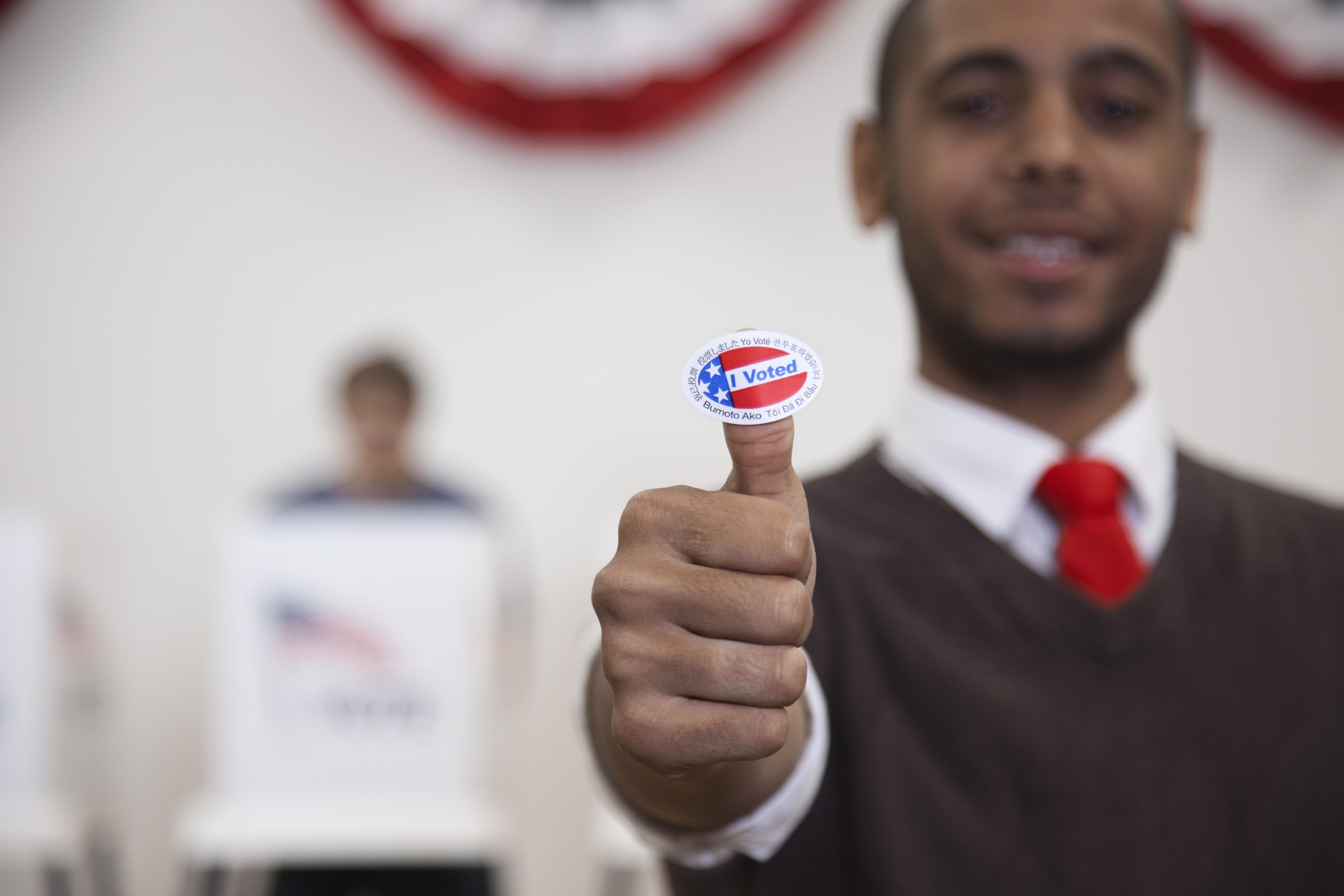 Hispanic voter holding an I Voted sticker in polling place