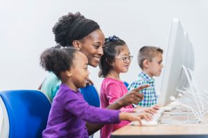 Teacher and elementary students in computer class