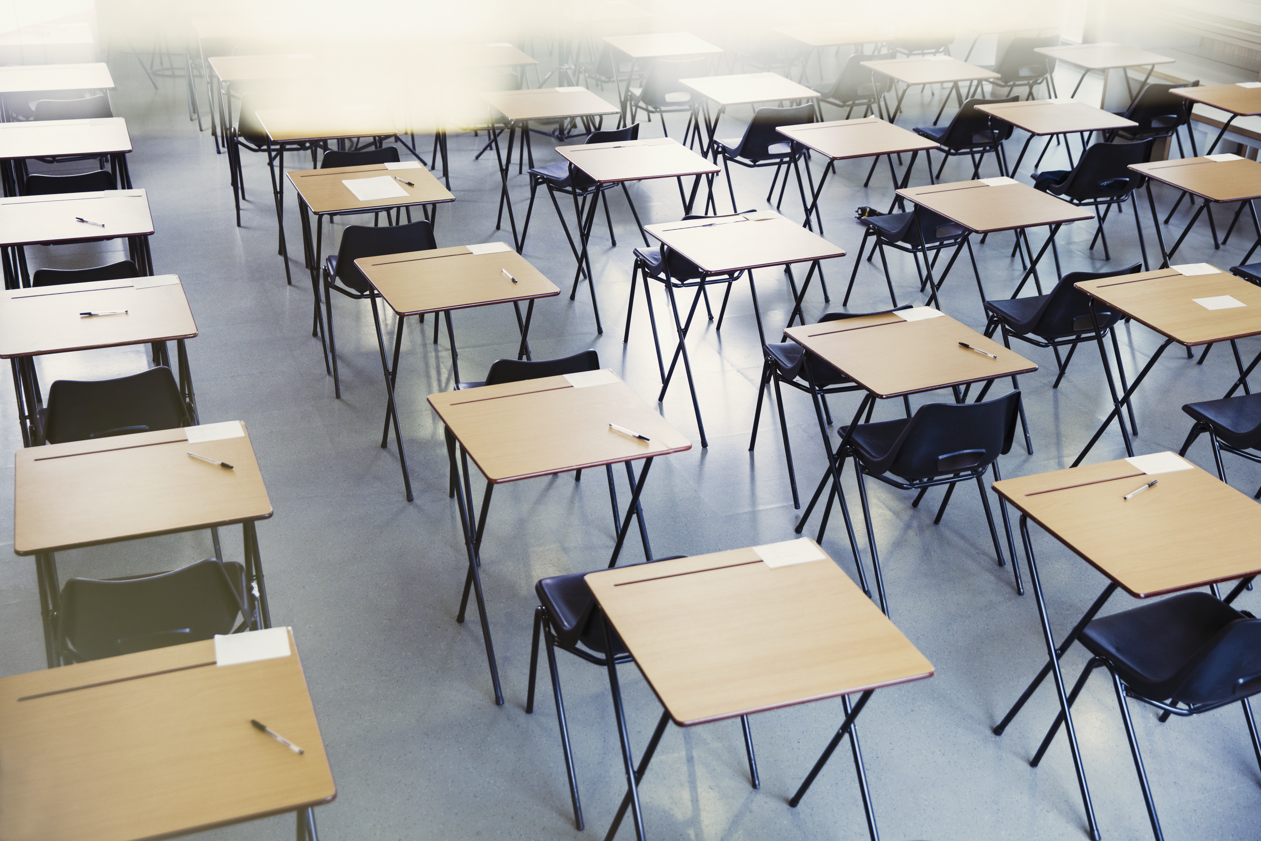 Pens and index cards on desks in empty classroom