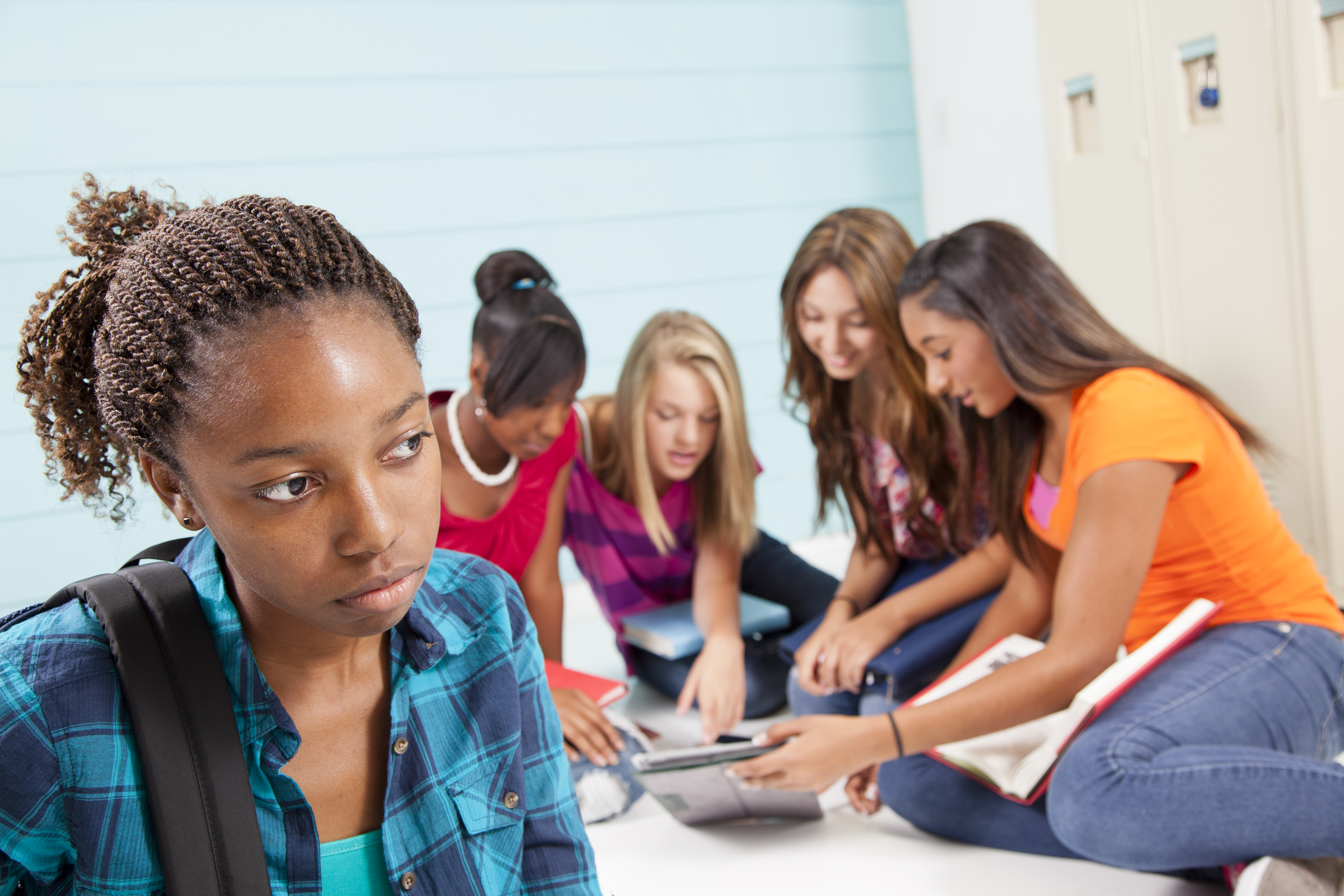 Teenage girls bully classmate. Gossip, talking. School hall. Lockers.