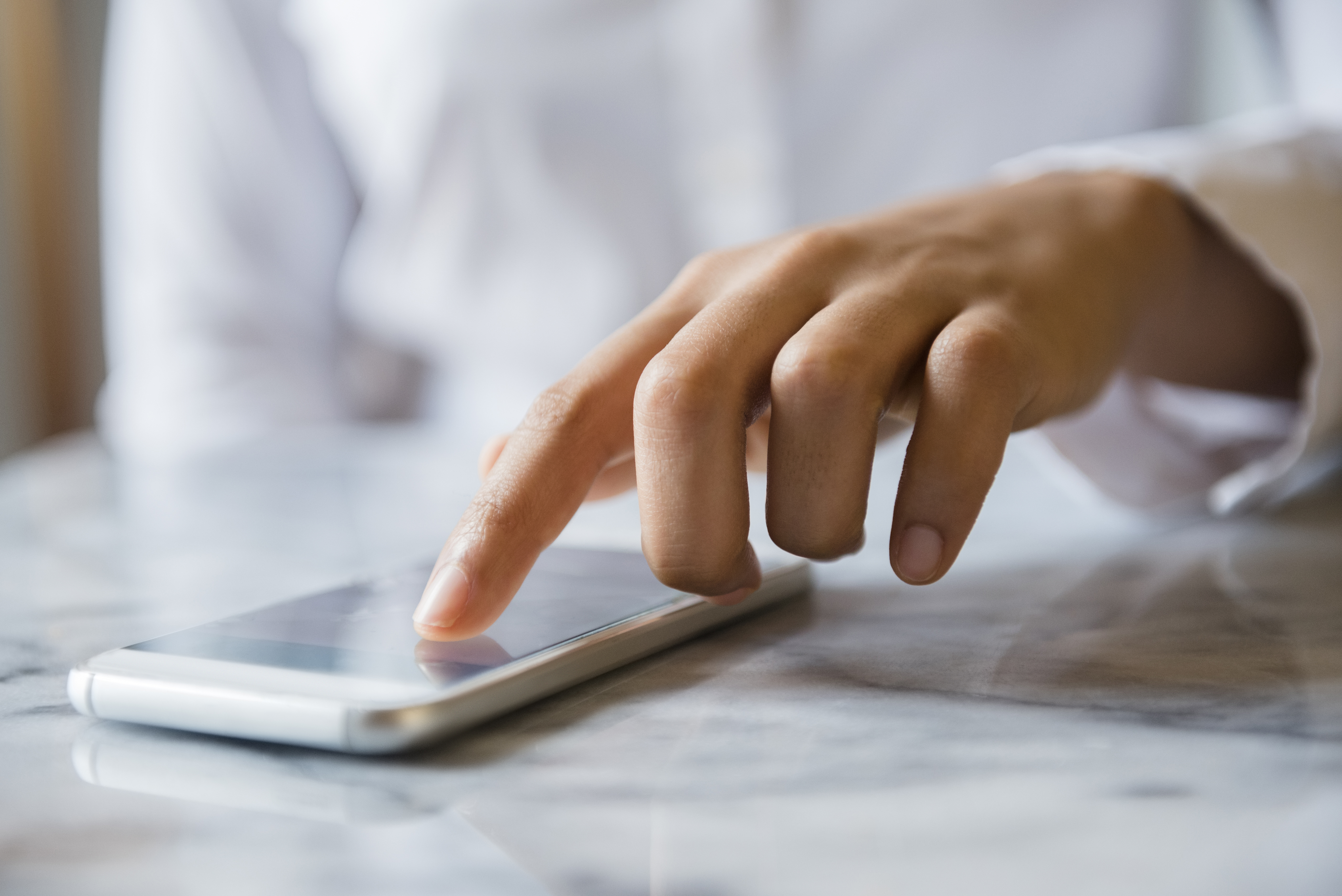 Finger of African American woman using cell phone