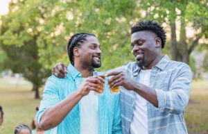 Two African-American men outdoors, drinking, talking