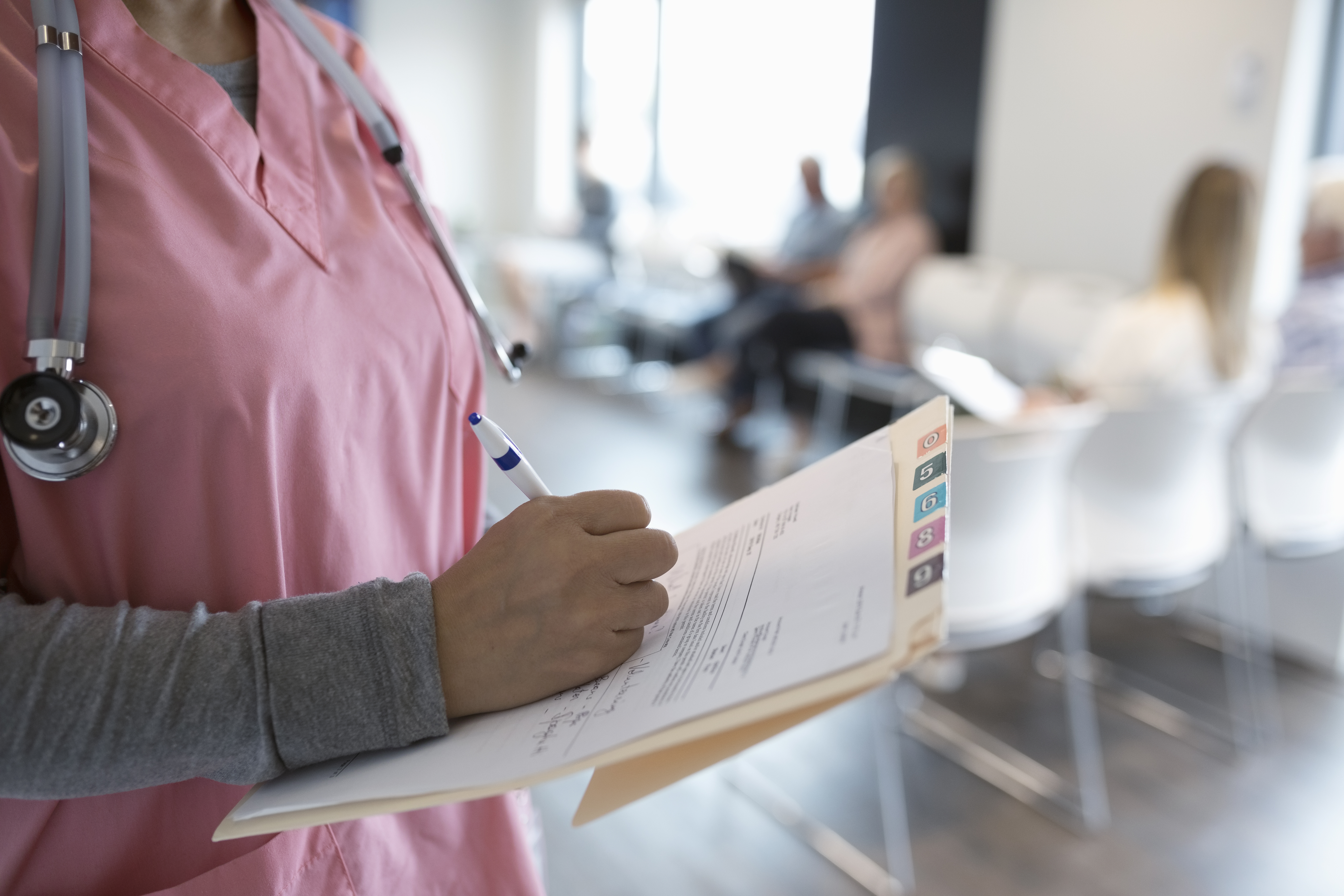 Close up female nurse writing on medical record in clinic waiting room
