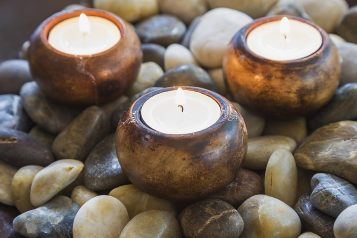 Close-up of lit tea light candles in dish of stones