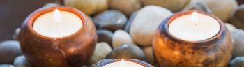 Close-up of lit tea light candles in dish of stones