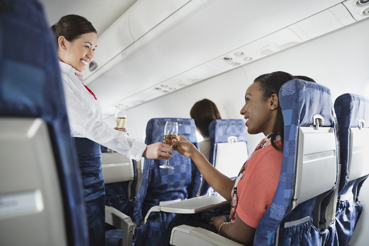 Flight attendant serving champagne to passenger