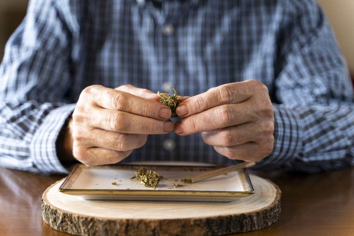 Senior man at home rolling marihuana joint