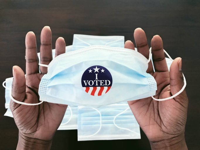 Woman Holds Face Mask With "I Voted" Sticker