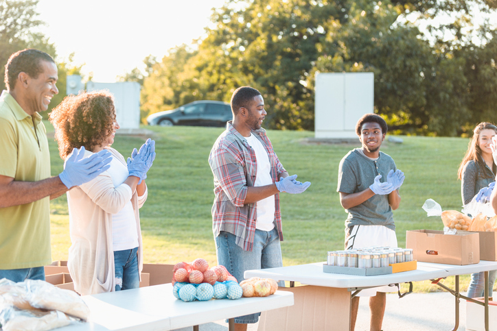 Diverse group of volunteers claps when people bring donated food