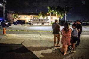Locals stand and wait for updates across the street from...