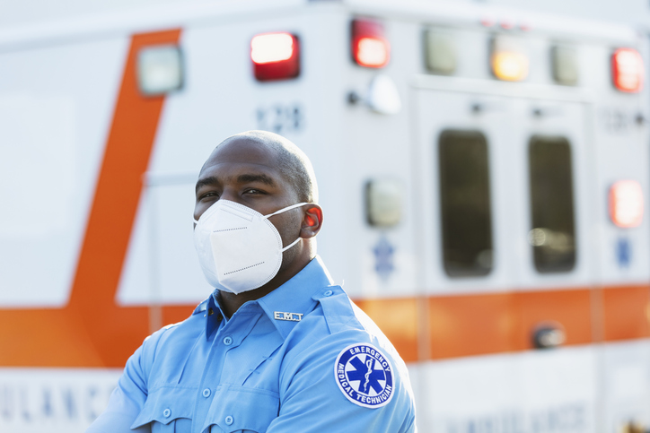 Paramedic in front of ambulance, with face mask