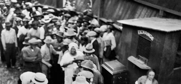 Group of African Americans, some standing in line next to Exchange Booth, during Race Riots, Tulsa, Oklahoma, USA, Alvin C. Krupnick Co. June 1921