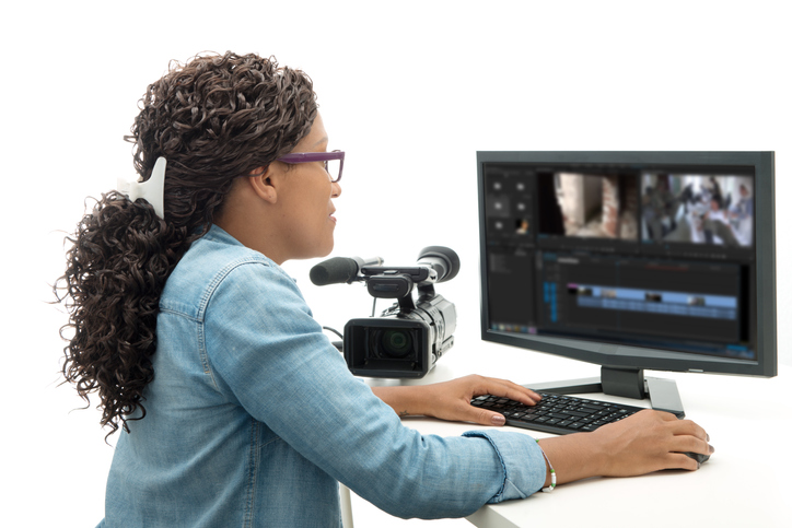 Woman Using Computer By Movie Camera Against White Background
