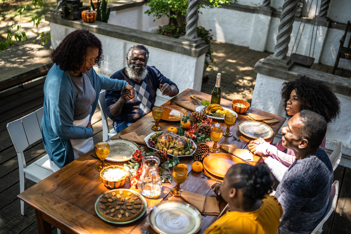 Senior woman saying grace before Thanksgiving lunch at home
