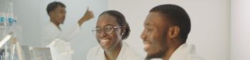 Diverse team working in modern laboratory. Woman and man joking during research