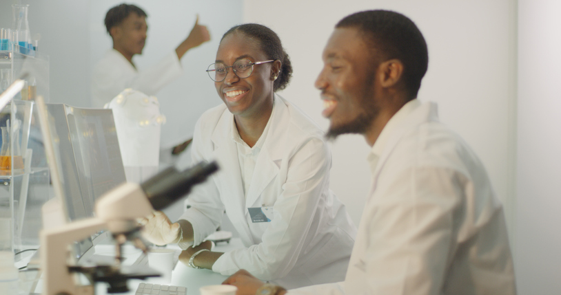 Diverse team working in modern laboratory. Woman and man joking during research