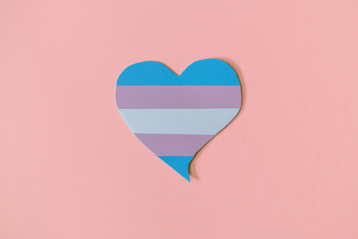 Paperboard heart with the transgender flag on a pink background
