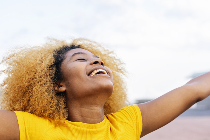 Portrait of positive young afro woman with closed eyes breathing fresh air outdoors