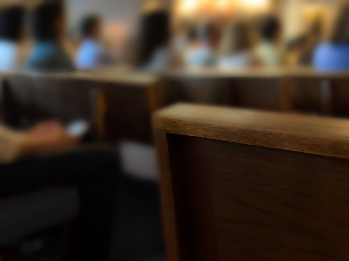 rear view of pews with unrecognizable people sitting