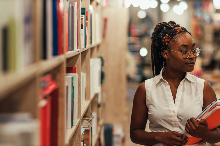 Student at a library choosing a book in the shelf