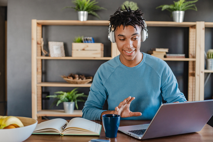 Young African-American man works on a laptop and communicates on a video call