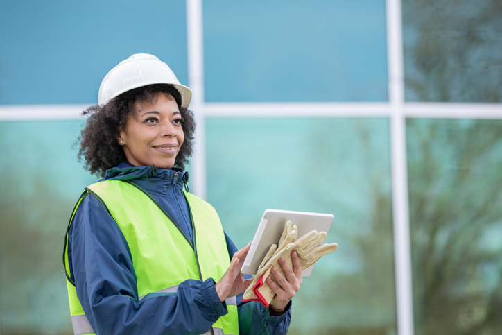 Woman is monitoring job site and using digital tablet