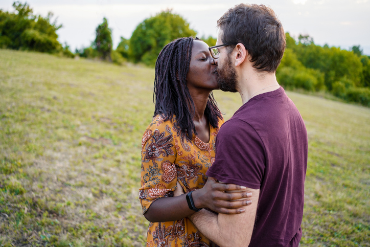 Happy multiethnic couple kissing on the hill