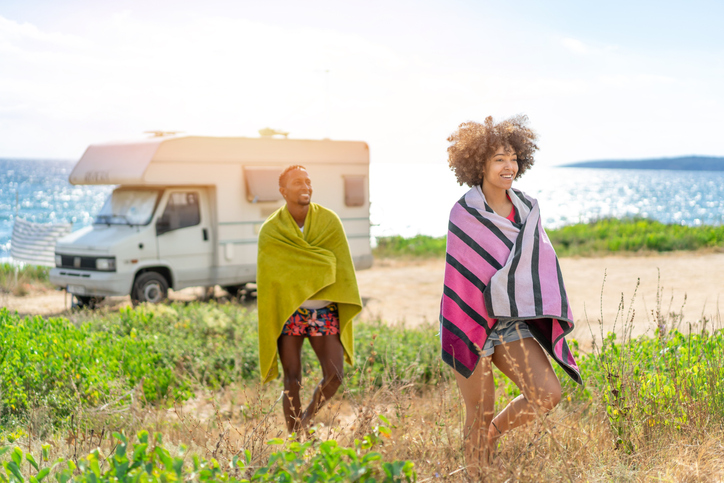 Afro couple in love enjoying their romantic summer vacation with camper