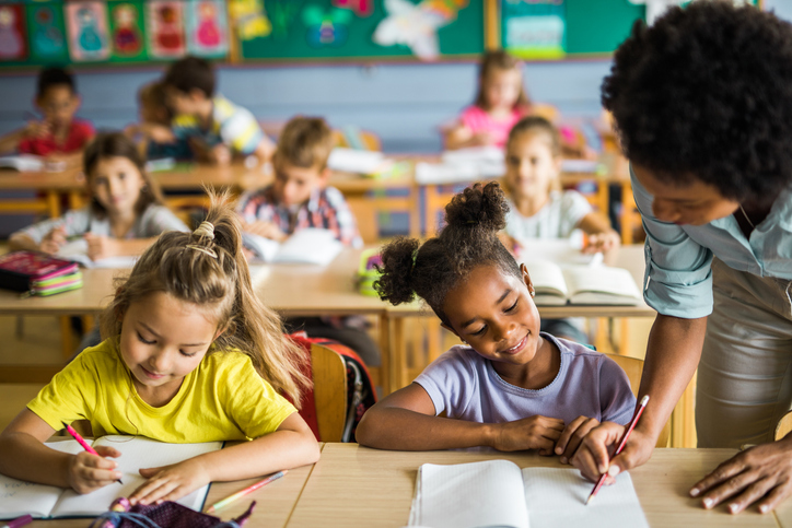 Black teacher assisting elementary students on a class.