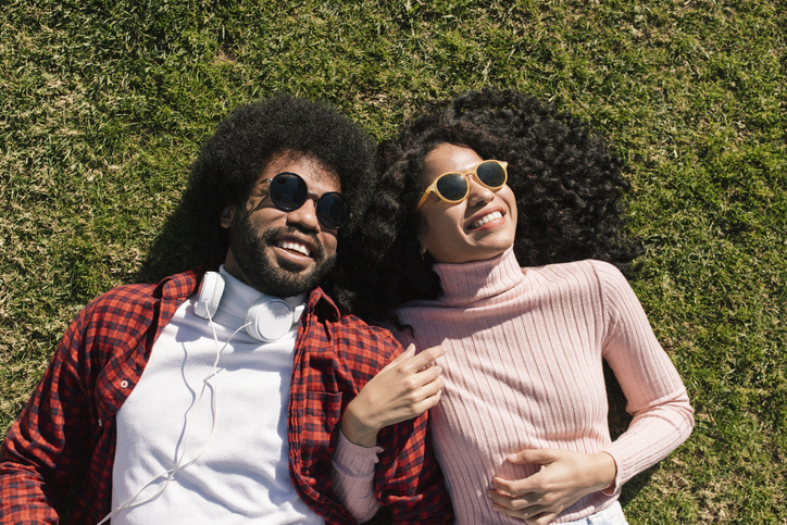 Happy couple wearing sunglasses lying on grass