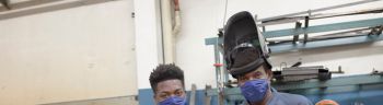 Portrait of two black workers on a grid with face mask at reopening factory.
