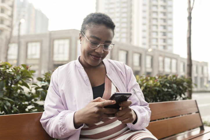 Young African woman reading text message on mobile phone