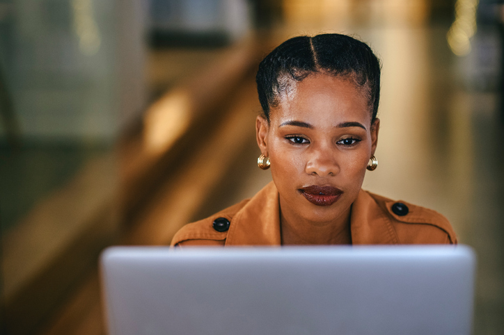 Creative designer in the fashion industry working on a laptop in her office. Serious business woman thinking about design ideas and planning a marketing strategy for her new business startup