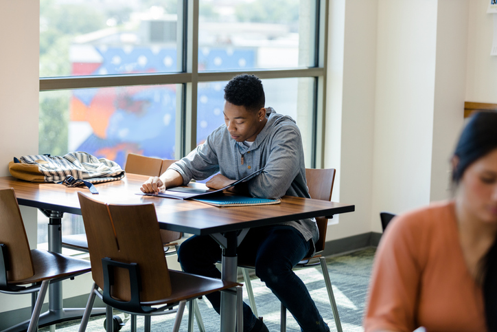 Male college student reviews notes before class