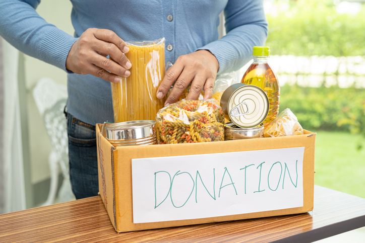 Volunteers putting various dry food in donation box for help people.