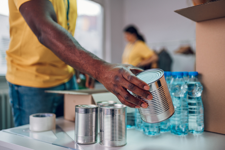 African american man hand holding food can while working ina donation center