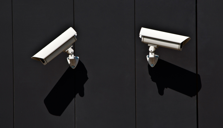 two surveillance cameras on the wall of a public building