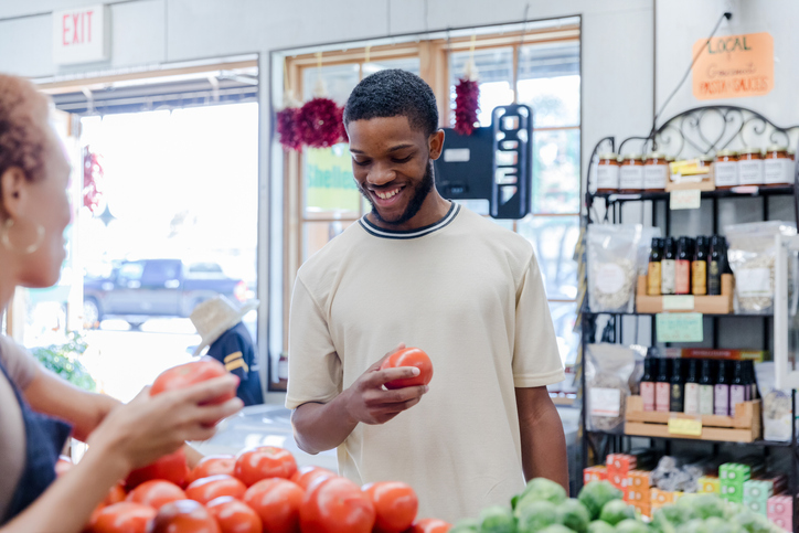 Female fresh food market owner helps young man with selections - stress