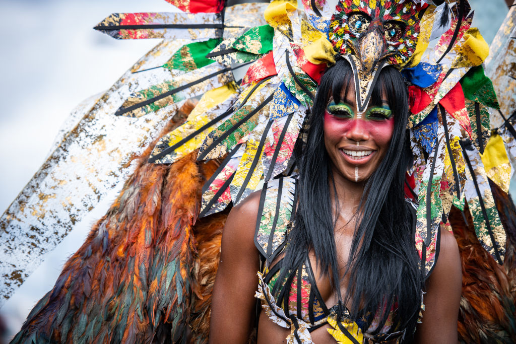 A performer wearing a costume participates in the Notting...