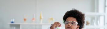 African elementary science student using chemistry set in elementary science classroom.