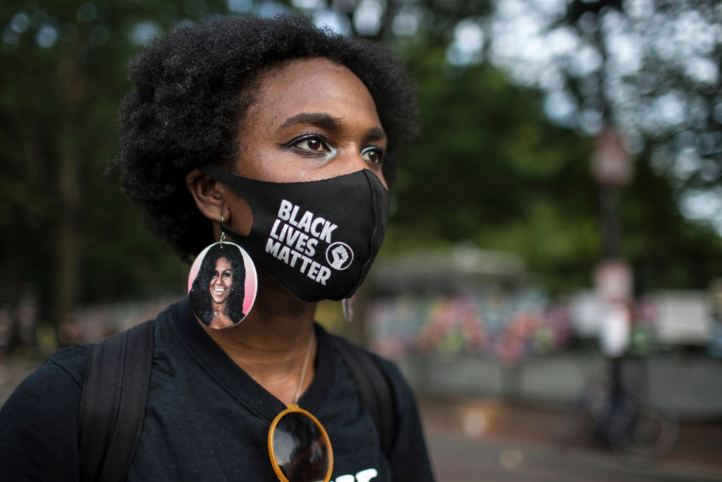 A young woman wearing protective mask with Black Lives...