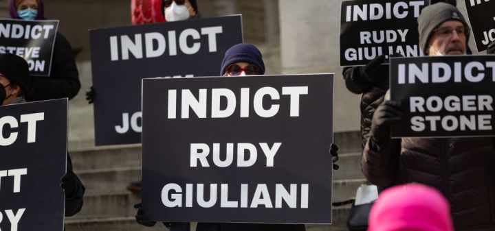Activist holding a placard indict Rudy Giuliani. Activists...