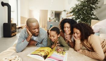 Happy black family reading a book in the living room.
